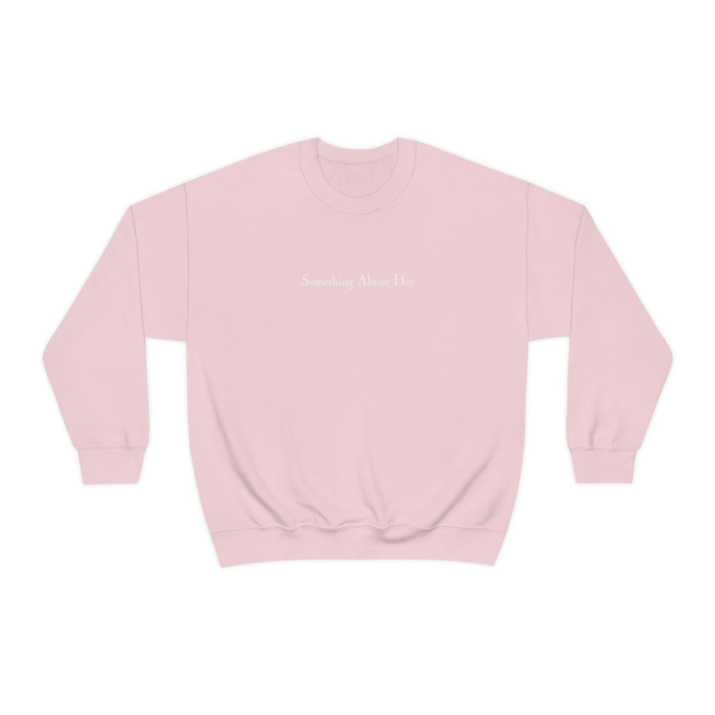 A pink crewneck sweatshirt with Something About Her embroidered across the chest in white