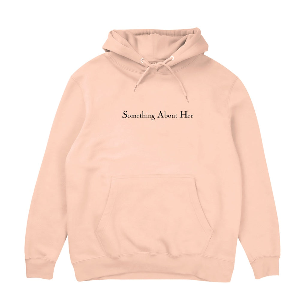A pale pink hooded sweatshirt with "Something About Her" embroidered across the chest in black