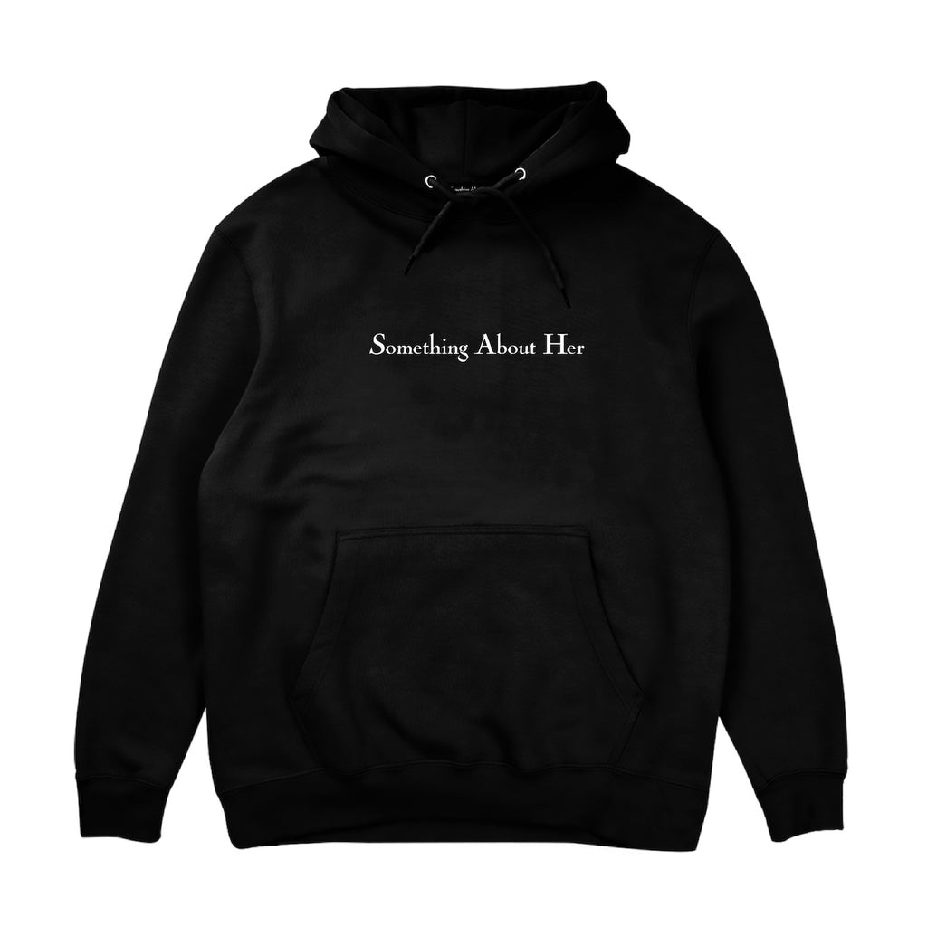 A black hooded sweatshirt with "Something About Her" embroidered across the chest in white