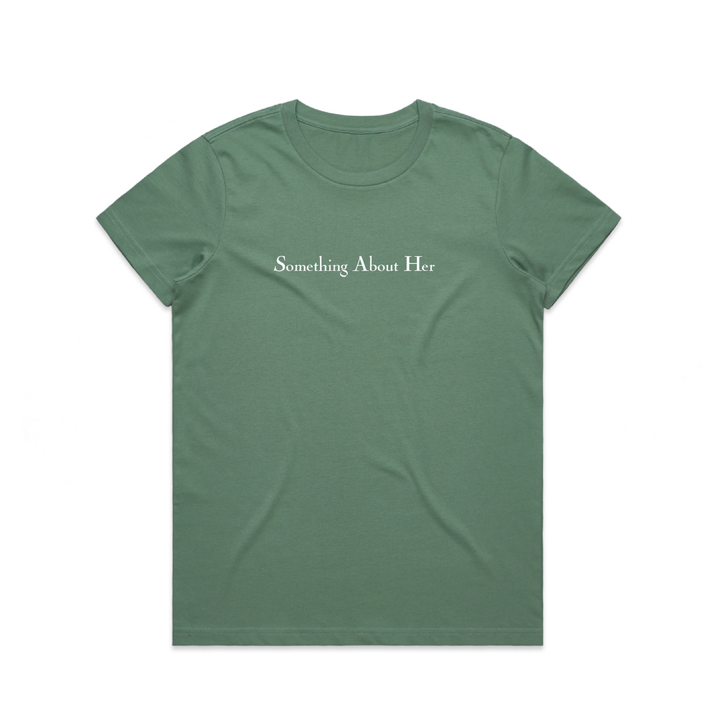 A green women's tee shirt with "Something About Her" printed across the chest in white