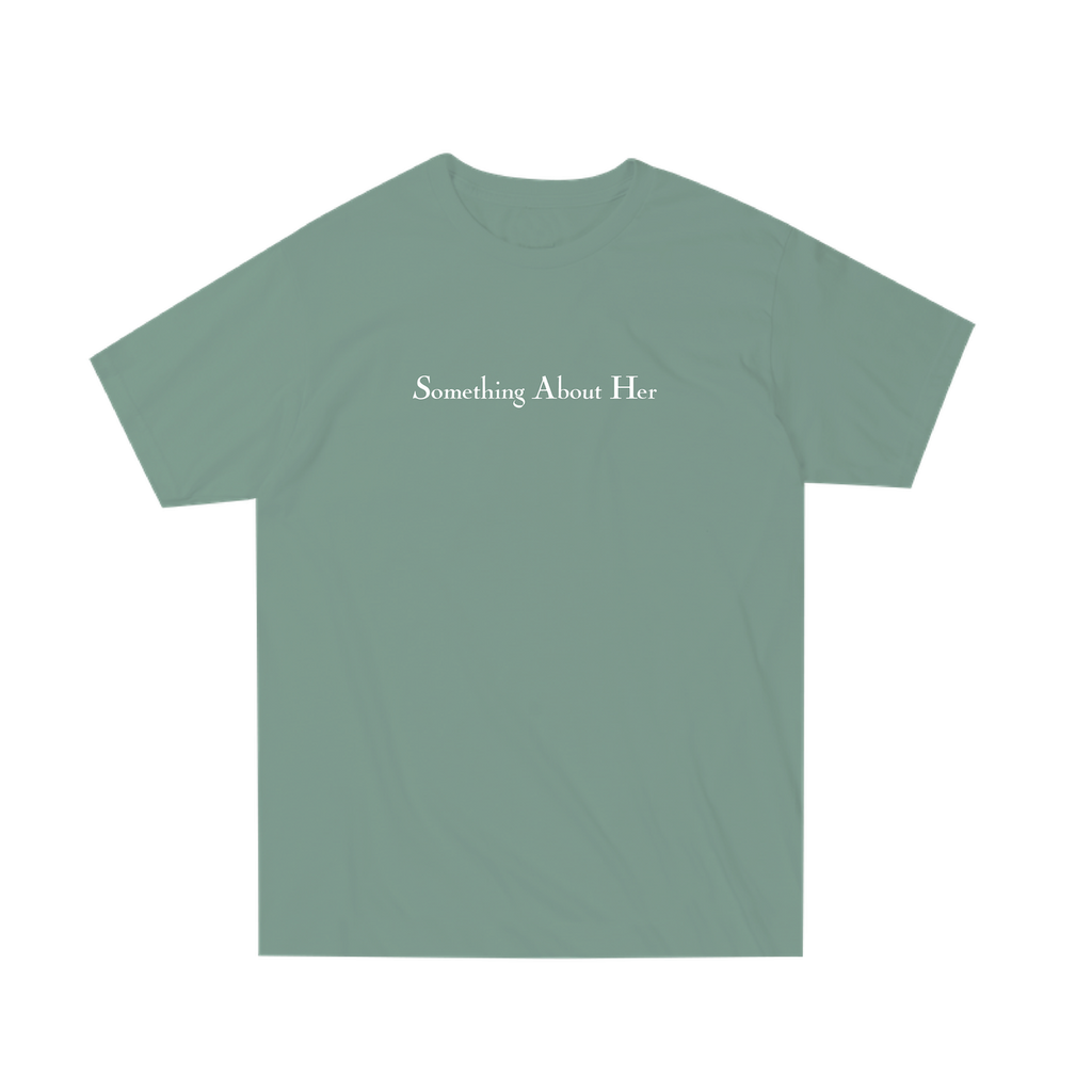 A green unisex tee shirt with "Something About Her" printed across the chest in white 