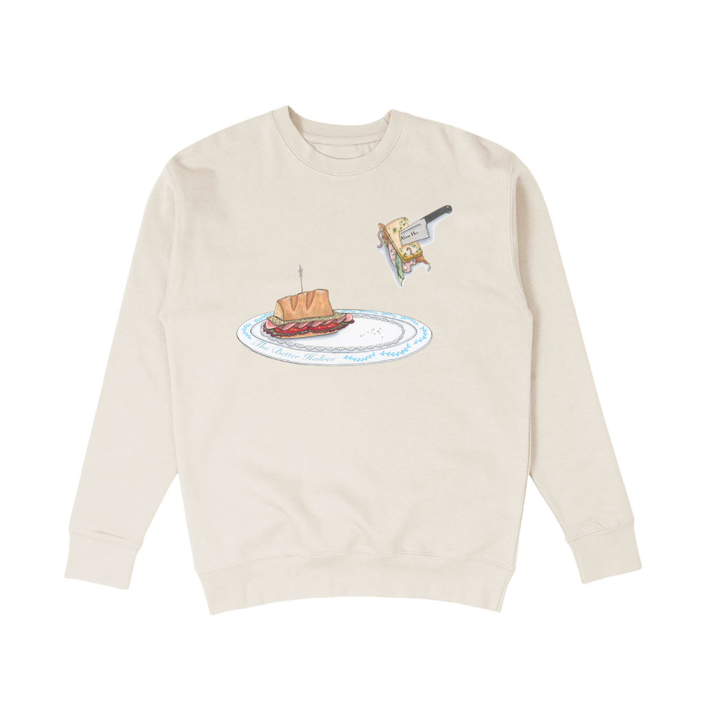 A bone (similar to tan) crewneck with a design of a sandwich on a plate printed across the center chest