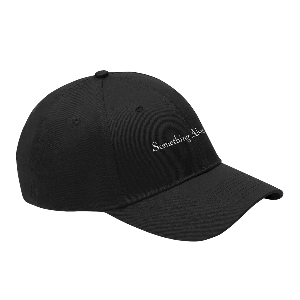 A side view of a black dad hat style cap with "Something About Her" embroidered in the middle in white
